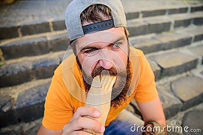 Junk food. Carefree hipster eat junk food while sit stairs. Guy eating hot dog. Snack for good mood. Unleashed appetite Stock Photo