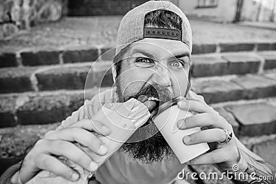 Junk food. Carefree hipster eat junk food while sit stairs. Snack for good mood. Guy eating hot dog. Street food concept Stock Photo