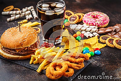 Junk food concept. Unhealthy food background. Fast food and sugar. Burger, sweets, chips, chocolate, donuts, soda Stock Photo