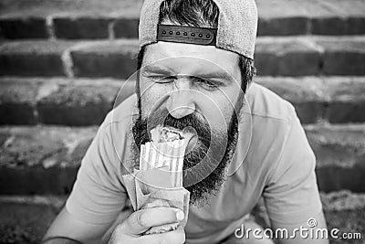 Junk food. Guy eating hot dog. Snack for good mood. Unleashed appetite. Street food concept. Man bearded eat tasty Stock Photo