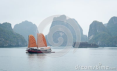 A junk sails through Halong Bay Stock Photo