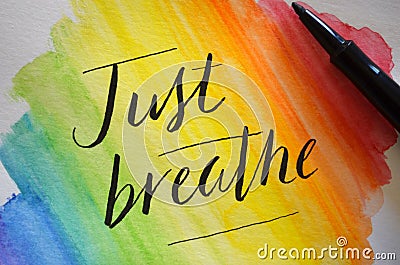 JUST BREATHE hand-lettered on rainbow watercolor background Stock Photo