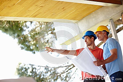 Just imagine it. Two man assessing their building progress while holding onto the blueprint. Stock Photo