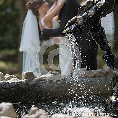 Just married behind fountain. Focus on foreground Stock Photo