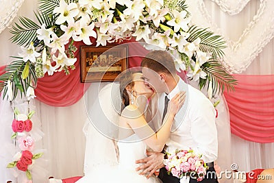 Just married kiss in the front of altar made of lilies Stock Photo
