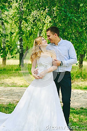 Just married loving hipster couple in wedding dress and suit on green field in a forest at sunset. happy bride and groom Stock Photo