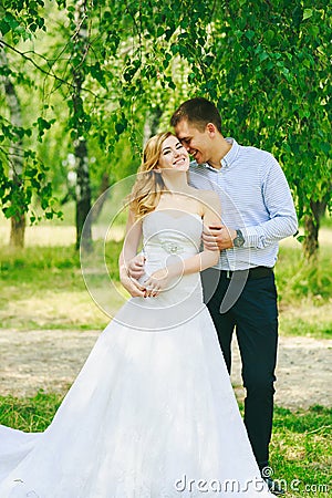 Just married loving hipster couple in wedding dress and suit on green field in a forest at sunset. happy bride and groom Stock Photo