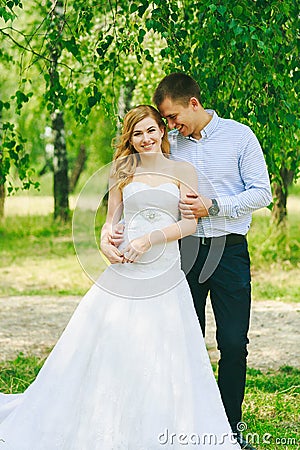 Just married loving hipster couple in wedding dress and suit on green field in a forest at sunset. happy bride and groom Stock Photo