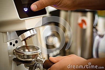 Just push the button. Fresh ground coffee in portafilter. Barista grind coffee beans using coffee machine. Coffee Stock Photo