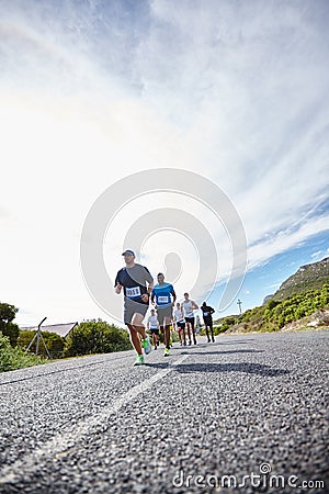 Just put one foot in front of the other. Low angle shot of a group of young men running a marathon. Stock Photo