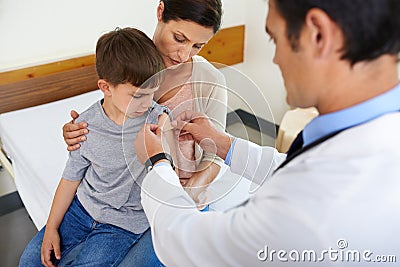 Just a teeny, tiny bit of ouch. Aerial shot of a doctor placing a plaster on his patients arm. Stock Photo