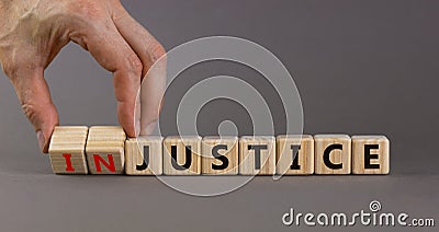 Justice instead of injustice. Hand turns cubes and changes the word `injustice` to `justice` on wooden cubes. Beautiful grey Stock Photo