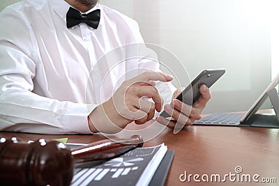 Justice and Law context.Male lawyer hand working with smart phone,digital tablet computer docking keyboard with gavel and Stock Photo