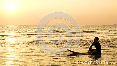 4K la silhouette de l'homme de surfer détendent en se reposant sur la planche de surf au-dessus de la mer au coucher du soleil su clips vidéos 4K la silhouette de l'homme de surfer détendent en se reposant sur la planche de surf au-dessus de la mer au coucher du soleil su clips vidéos