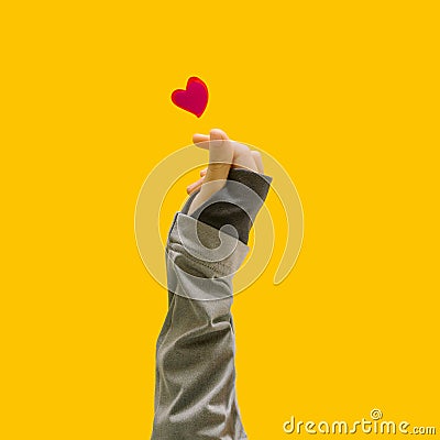 K pop concept. A girl teenager hand showing finger heart gesture. Red heart above. Unique yellow background Stock Photo
