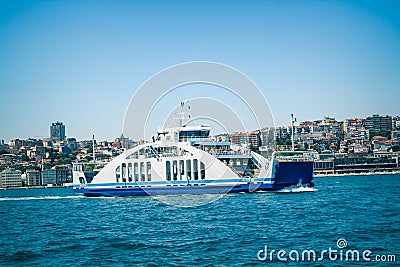 Wide angle view of blue white ferryboat carrying cars and vehicles moving on Marmara Sea and city appears behind in a clear air Editorial Stock Photo