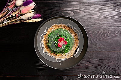 Kaiso with nut sauce and sesame in a black plate on a wooden background Stock Photo