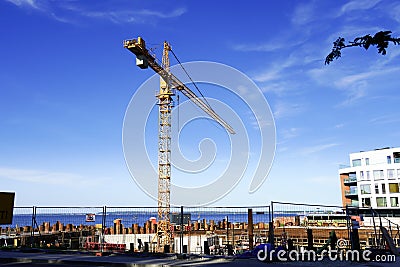 Yellow industrial crane with boom towards blue sky at summer time. Blue sea on the back Editorial Stock Photo