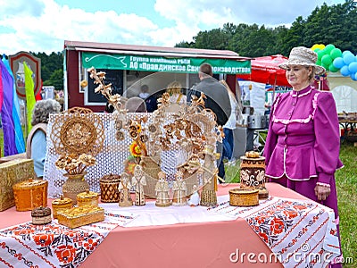 KALININGRAD REGION, RUSSIA. The elderly lady sells birch bark products at a fair of folk art Editorial Stock Photo