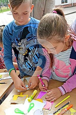 The boy and the girl are engaged in applique from color paper. Children`s master class in the open air Editorial Stock Photo