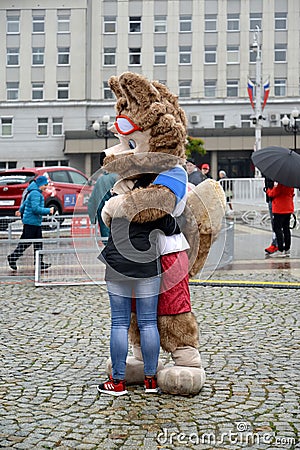 KALININGRAD, RUSSIA. A mascot of the FIFA World Cup of FIFA 2018 Zabivak`s wolf cub embraces the girl Editorial Stock Photo