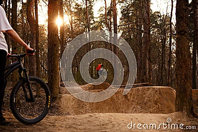 Cyclists in the forest on a track with slides for sport mountain Biking. Mountain bike jumping, extr Editorial Stock Photo