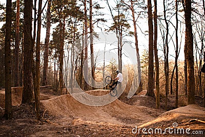 Cyclists in the forest on a track with slides for sport mountain Biking. Mountain bike jumping, extr Editorial Stock Photo