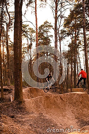 Cyclists in the forest on a track with slides for sport mountain Biking. Mountain bike jumping, extr Editorial Stock Photo