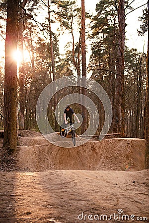 Cyclists in the forest on a track with slides for sport mountain Biking. Mountain bike jumping, extr Editorial Stock Photo