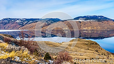 Kamloops Lake with the surrounding mountains reflecting on the quiet surface Stock Photo