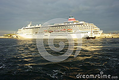 Sun rays break through storm clouds in the evening sky. Cruise ship Asuka II at sunset Editorial Stock Photo