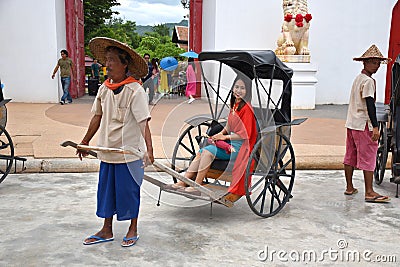 Kanchanaburi, Thailand, 09.09.2019: Beautiful Thai girl in traditional Thai, Siamese dress in an old rickshaw in front of the Editorial Stock Photo