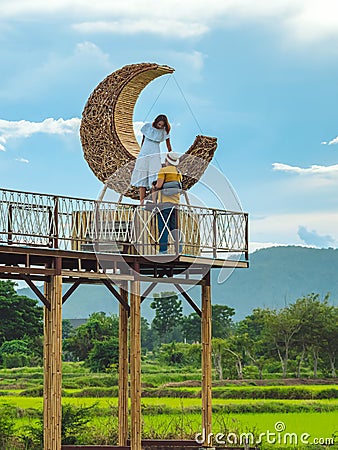 KANCHANABURI-THAILAND, SEPTEMBER 13, 2020 : Happy young couple take photo with crescent moon chair made of rattan for relaxation Editorial Stock Photo