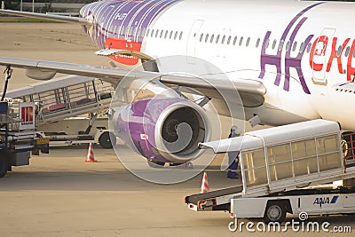 Airplane loading off its passengerst and cargo at Kansai International airport Editorial Stock Photo