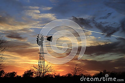 Kansas Awesome Sunset with colorful clouds, and a farm Windmill silhouette . Stock Photo