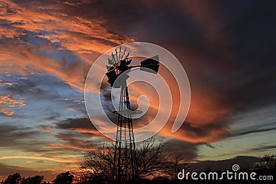 Kansas Awesome Sunset with colorful clouds, and a farm Windmill silhouette . Stock Photo