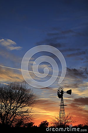 Kansas Awesome Sunset with colorful clouds, and a farm Windmill silhouette . Stock Photo