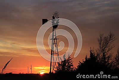 Kansas Windmill sunset with a tree silhouette with a colorful sky Stock Photo