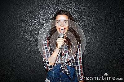 Karaoke party. Time to sing! Crazy casual curly chic girl singing with microphone. Studio shot Stock Photo