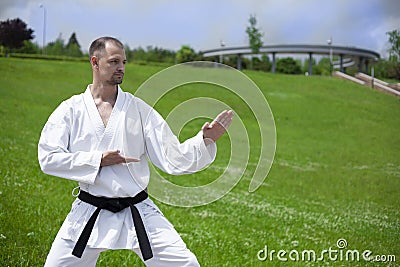 Karate training on a green lawn. A karate trainer is wearing a white kimono. Stock Photo