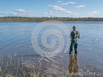 Man fishing with spinning in lake. Ecotourism, visiting fragile, pristine, undisturbed natural Stock Photo