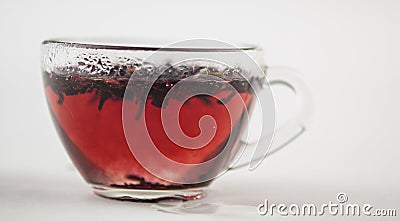 Tea drink in a glass. Red liquid in a glass. Dried petals. Hibiscus. Sudanese rose Stock Photo