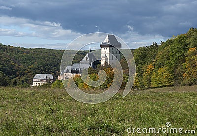 Karlstejn gothic state castle near Prague, the most famous castle in Czech Republic with grass meadow and autumn colored trees and Stock Photo