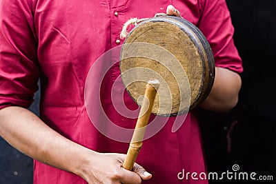 Kasar or gong bell being performed or hit with wooden stick by Indian male in traditional attire during hindu puja rituals. Kasar Stock Photo