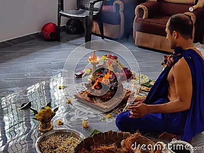 An Indian Hindu priest or Brahmin men doing Pooja or pray Ganapathi homam in the home with materials and vegetable food items Editorial Stock Photo