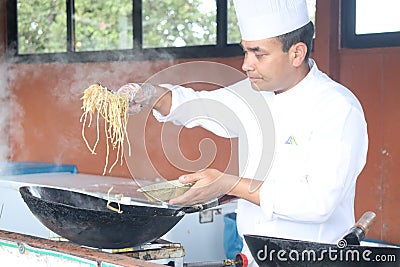 The celebrity chef is preparing exotic Thai noodles on the Chinese wok for a tv show. Editorial Stock Photo