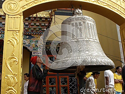 A man prays next to a large bell at the Boudhanath stupa in Kathmandu, Nepal Editorial Stock Photo