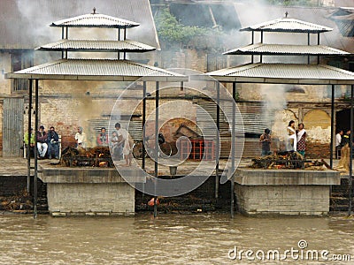 People next to two corpses being cremated on two funeral pyres at the Pashupatinath temple in Kathmandu, Nepal Editorial Stock Photo