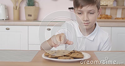 Kaukasiër die uit de tafel kijkt om een koekje te nemen en weg te rennen uit de keuken. portret van schattig stock videobeelden Kaukasiër die uit de tafel kijkt om een koekje te nemen en weg te rennen uit de keuken. portret van schattig stock videobeelden