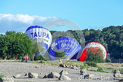 Kaunas, Lithuania 20 10 2022: Three blue and red air balloons on lawn between green trees lying before being fully Editorial Stock Photo